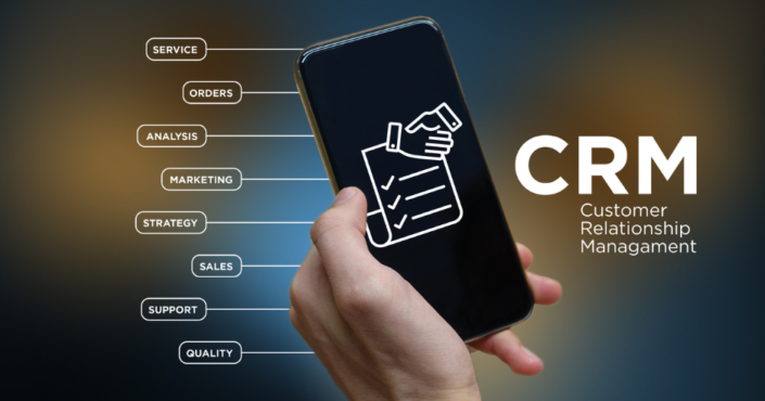 A person's hand holding a smartphone with the letters CRM displayed on the screen. The image highlights the benefits of using a CRM system, such as improved customer relationship management, increased sales and efficiency, and enhanced data analysis capabilities.